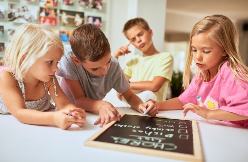 kids listing their household chores on a chalk board